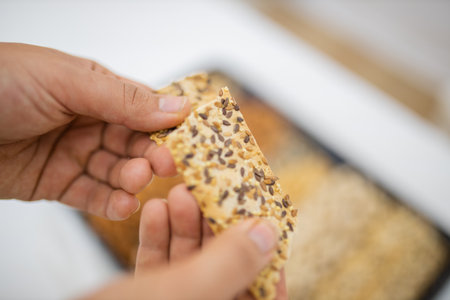 Female hand holding multi-seed crispbread above a tray with seeds and nutsの写真素材