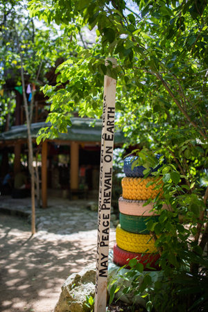 Peace pole message next to colorful stacked tires and a treeの写真素材