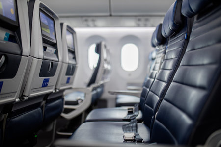 Empty dark blue seats with screens in the back inside an airplaneの写真素材