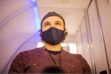 Self-portrait of a man wearing face mask in airplane bathroom