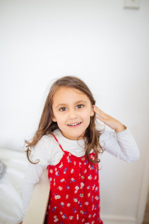 Cute little girl smiling and wearing a red-flowered dressの写真素材