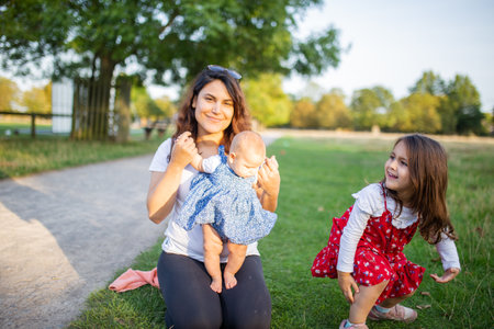 Happy woman and her daughters playing on the grassの写真素材