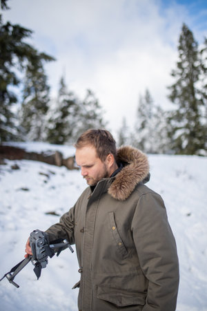 Handsome man holding a drone with snowy pines as background