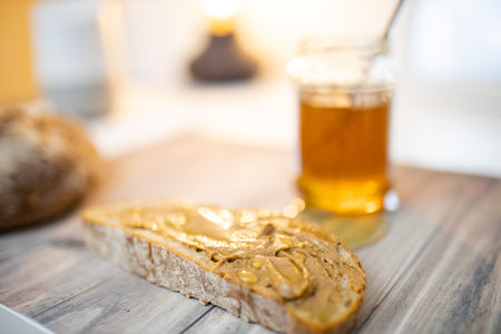 Slice of bread with peanut butter and a honey jar on wooden tableの写真素材