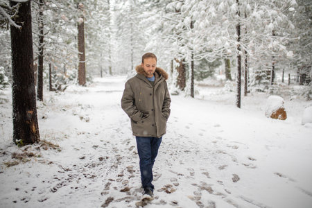 Man calmly walking in the middle of a snowy forestの写真素材