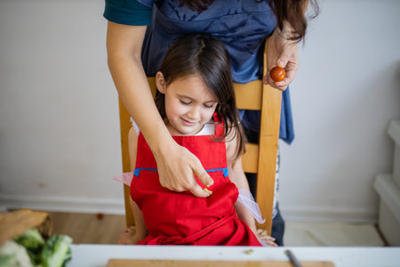 Happy mother and daughter at a table playing with their foodの写真素材
