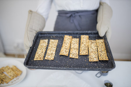 Gloved hands holding a black tray of Swedish crispbread
