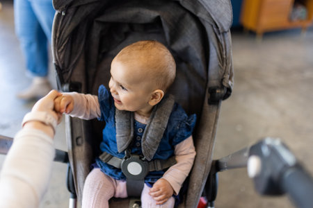 Adorable happy baby in a gray stroller in restaurantの写真素材