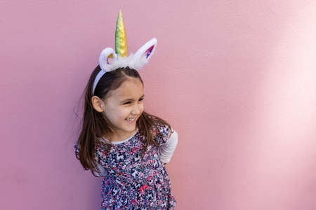 Adorable little girl wearing a unicorn headband with pink backgroundの写真素材