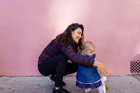 Happy mother and cute baby wearing unicorn headband with pink backgroundの写真素材