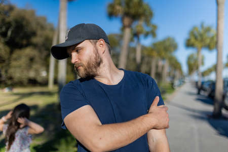 Bearded man standing with palm trees and blue sky as background