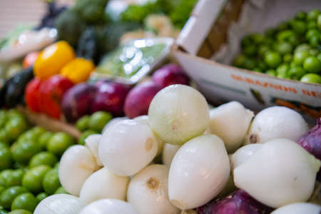 Colorful vegetables stand with onions, green tomatoes, bell peppers, and more