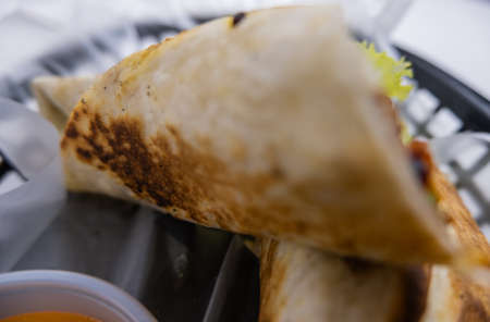 Spicy pork burritos and sauce in a plastic basket