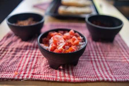 Black bowls of pico de gallo above checkered tableclothの写真素材