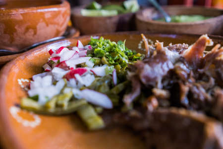 Mexican chopped lamb meat, hot sauces, and lime slices in clay bowlsの写真素材
