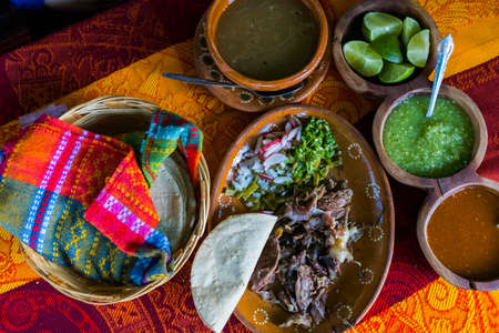 Mexican chopped lamb meat, hot sauces, and tortillas on colorful tableclothの写真素材