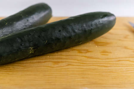 Fresh cucumbers isolated on a wooden cutting boardの写真素材