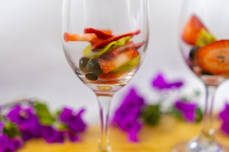 Strawberry and kiwi slices in wine glasses with white backgroundの写真素材