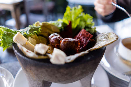White cheese slices, lettuce, chorizo, and roasted nopales in Mexican molcajeteの写真素材