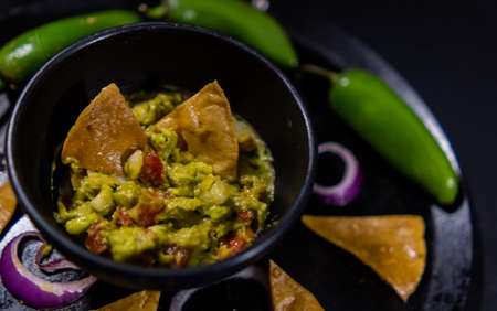 Bowl of guacamole on Mexican comal decorated with tortilla chips and vegetablesの写真素材
