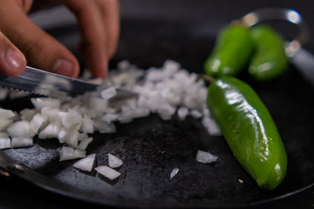Hands chopping onion and green chili peppers on a traditional Mexican comalの写真素材