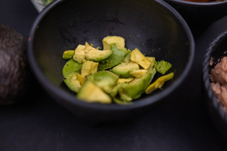 Small bowl of chopped avocado on black surfaceの写真素材