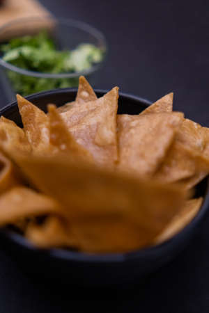 Bowls of tortilla chips and chopped lettuce with black backgroundの写真素材