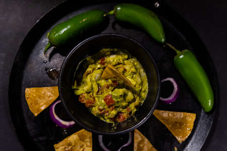Bowl of guacamole on Mexican comal decorated with tortilla chips and vegetablesの写真素材