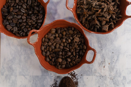 Pots of coffee beans and anise seeds on white marble surfaceの写真素材