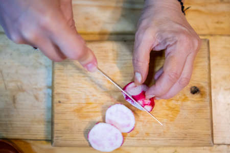 Hands slicing fresh radish on a cutting boardの写真素材