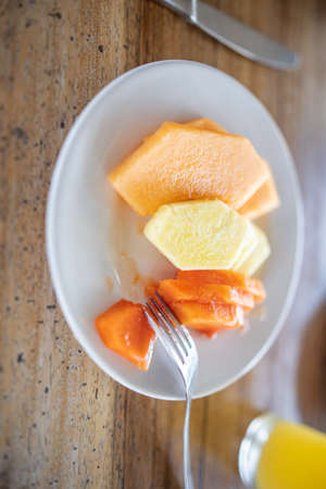 Delicious pineapple, melon, and papaya slices on wooden table