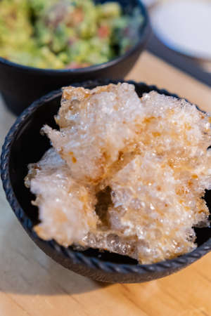 Bowls of pork rinds and guacamole on wooden surfaceの写真素材