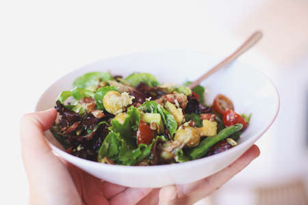 Hand holding a bowl of healthy saladの写真素材