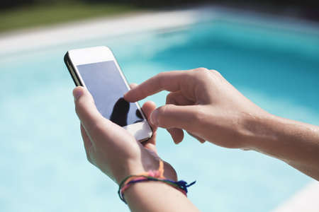 A woman using a smartphone in a swimming poolの写真素材