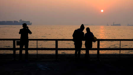 a couple of lovers are dating and a man is taking photos at sunsetの写真素材