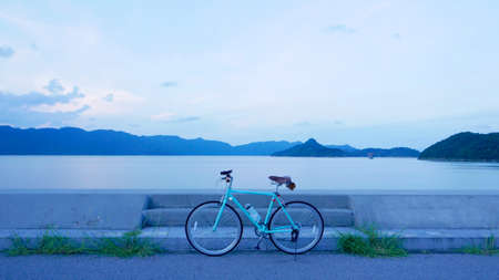 Bicycle, road, cloud and lake in the early evening