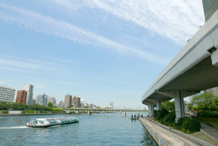 Sightseeing boat in Japan river, residential apartments and bridge