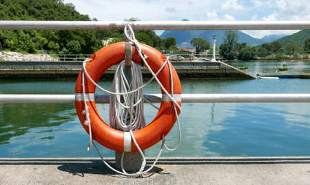 Red lifebelt, safety rope, pier near the lake