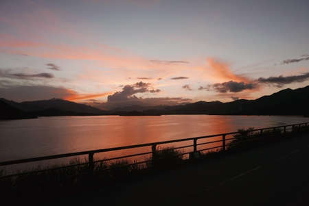 The silhouette of mountain, plant, fence, gradient sky and ocean at sunsetの写真素材