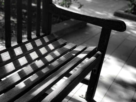 Black and white garden wooden bench with the day light and shadowの写真素材