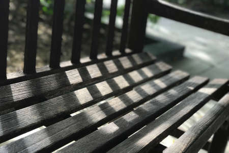 Garden dark brwon wooden bench with the day light and shadowの写真素材