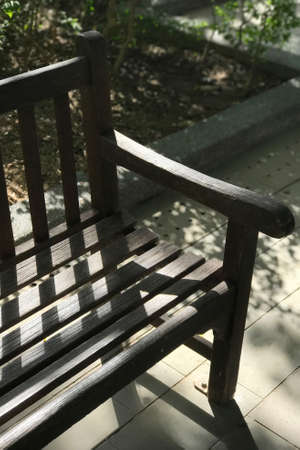 Garden dark brwon wooden bench with the day light and shadowの写真素材