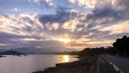 Boat on the ocean and car on the road at sunsetの写真素材