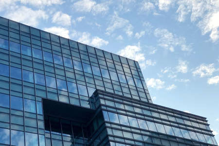 Commerical office building with the reflection of blue sky and cloudの写真素材