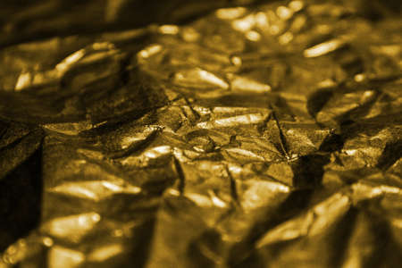 The golden shiny abstract metallic crumpled paper backgroundの写真素材