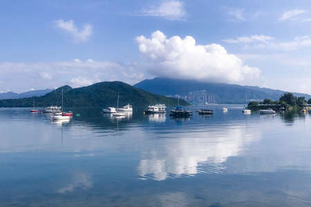 Horizontal mountain, blue sky, yacht boats and cloudscape with reflection on the lakeの写真素材