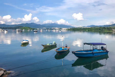 Mountain, cloudscape, fishing boats and yacht on the lakeの写真素材