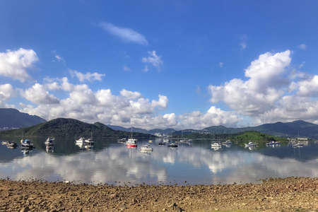 Horizontal mountain, blue sky, yacht boats and cloudscape with reflection on the lakeの写真素材