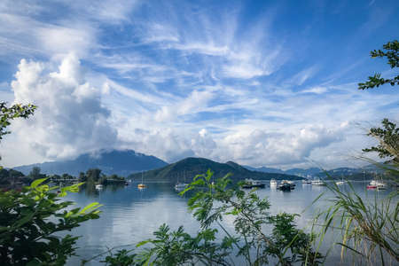 Green plants, mountain, blue sky, boats, yacht and sailboats on the lakeの写真素材