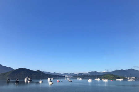 Mountain, blue sky, boats, yacht and sailboats on the lakeの写真素材
